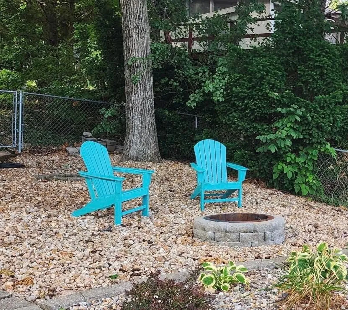 A cozy outdoor fire pit scene surrounded by turquoise chairs and lush greenery. The setup is inviting for evening gatherings, fireside chats, and unwinding after a night out under the stars.