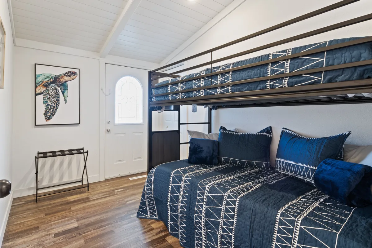 A playful bunk bed setup with blue bedding, whimsical turtle wall art, and a cozy atmosphere, ideal for families or groups. The space feels inviting and comfortable, suitable for both children and adults looking to unwind after a day at the lake.