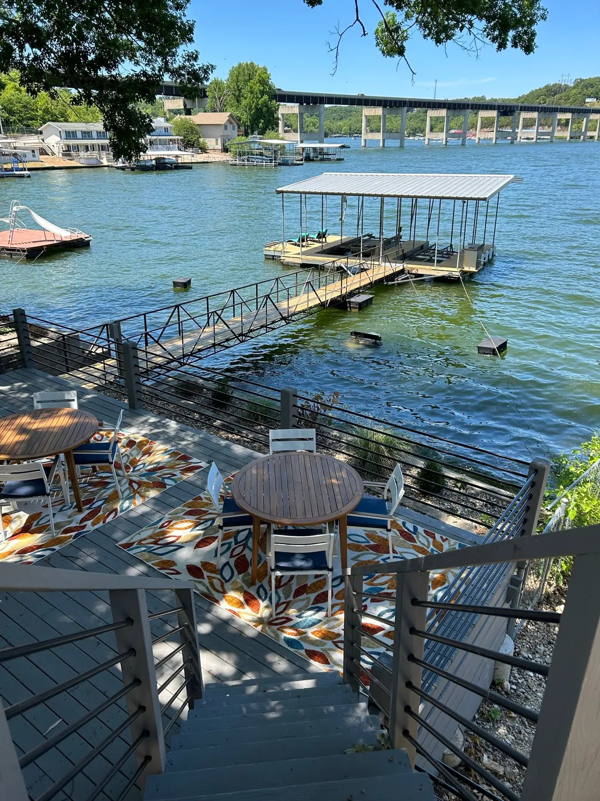 This image features a lake view with a private dock, outdoor seating, and decorative rugs. The dock is situated directly on the water, inviting guests to relax, fish, or set off on boating adventures. The cozy outdoor furniture and proximity to the shoreline create a welcoming atmosphere for lakeside activities.