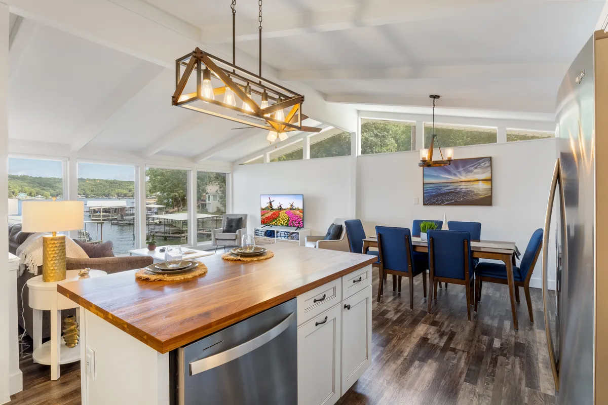 A stylish kitchen island opens into a dining area with large windows overlooking the water. The space features modern appliances, a beautiful art piece, and great natural light, making it ideal for both casual mornings and special-occasion meals.